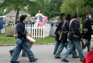 Alyssa Gonzales is dressed as Lucy Hood in Civil War era clothing. She's taken off a petticoat with an American flag, waving it to Union soldiers as they march by.
